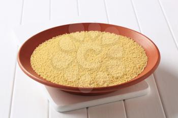 Dried couscous in a terracotta bowl