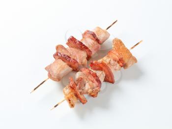 Two pork and bacon skewers - studio shot