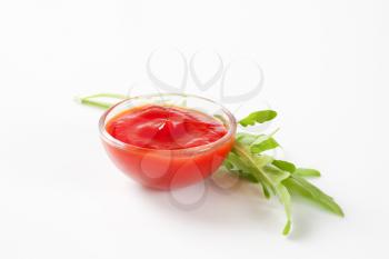 Small bowl of ketchup and arugula leaves
