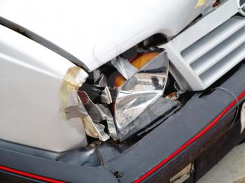 Detail of broken front headlight on white car
