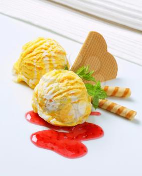 Scoops of ice cream with raspberry sauce and wafers
