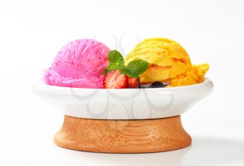 Two scoops of fruit flavored ice cream with fresh strawberries