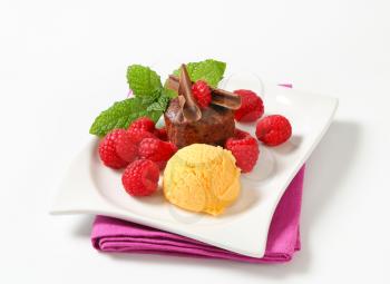 Mini chocolate cake served with fresh raspberries and scoop of ice cream