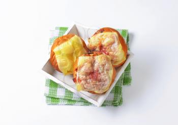 Bread buns with slices of cheese and ham on top