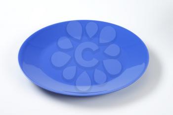empty blue dinner plate on off-white background