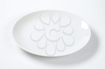 empty rimless white plate on off-white background