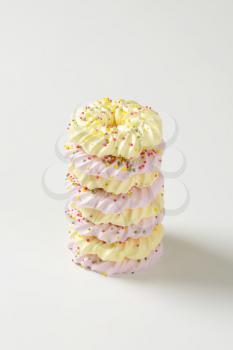 Stack of wreath-shaped meringue cookies topped with sprinkles
v