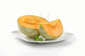 cantaloupe melon on white plate - half and slice