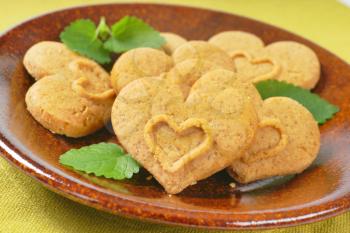 detail of heart-shaped cookies and mint on brown plate