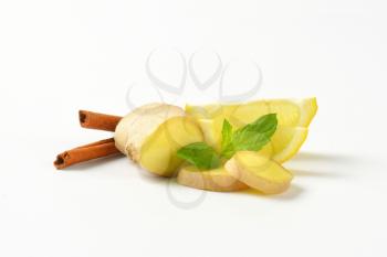 sliced ginger with lemon and cinnamon sticks on white background