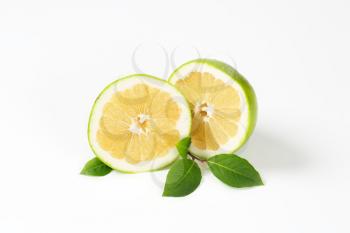 halved green grapefruit on white background