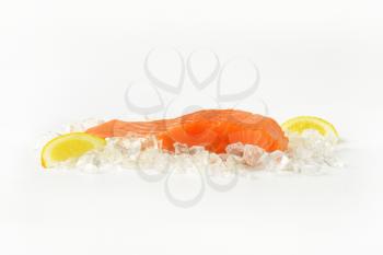 raw salmon fillet with slices of lemon on ice