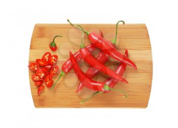 whole and sliced chili peppers on wooden cutting board