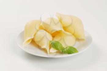 plate of cooked pasta shells on white background