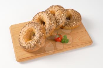 fresh bagels topped with seeds on wooden cutting board