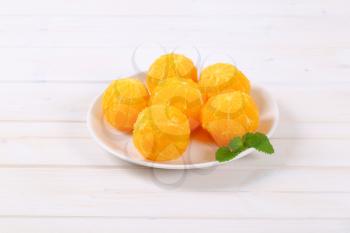 plate of whole peeled oranges on white background