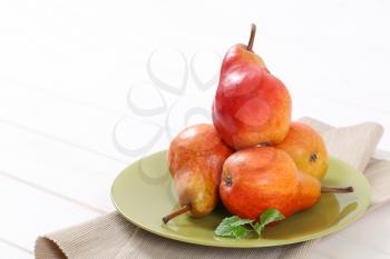 plate of ripe red pears on white background - close up