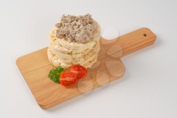 slices of puffed rice bread with fish spread on wooden cutting board