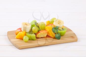 pile of fresh fruit salad on wooden cutting board