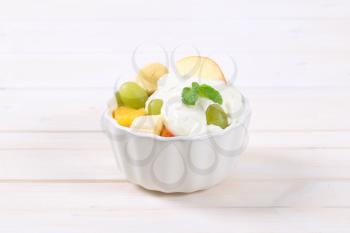 bowl of fresh fruit salad with white yogurt on white background