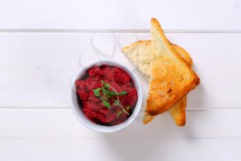 cup of fresh beetroot puree with toast on white wooden background
