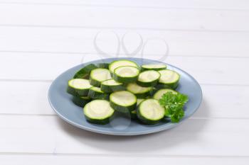 plate of green zucchini slices on white wooden background