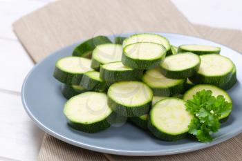 plate of green zucchini slices on beige place mat - close up