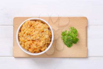 Bowl of cooked red lentils on cutting board