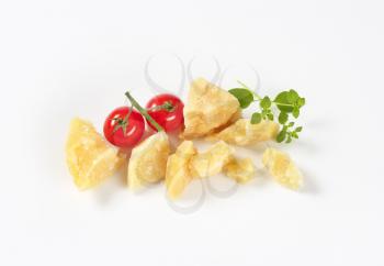 pieces of fresh parmesan cheese and cherry tomatoes on white background