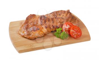 two slices of grilled pork meat on wooden cutting board