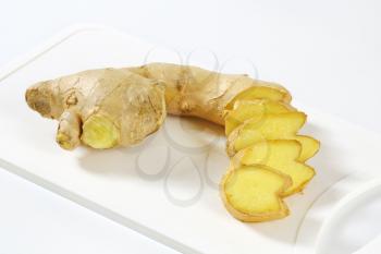 Fresh ginger root, sliced on white cutting board