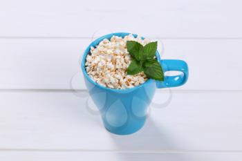 cup of puffed buckwheat on white wooden background