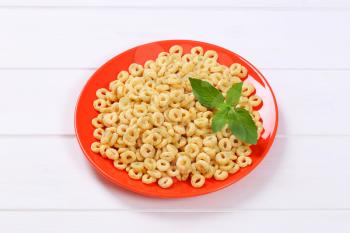 plate of honey cereal rings on white wooden background