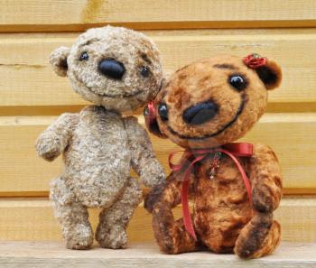 Teddy bears against a wooden wall. Handmade, the sewed plush toys