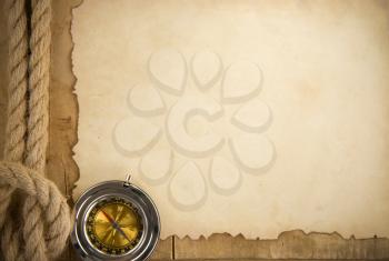 ship ropes and compass on old paper parchment background at woood