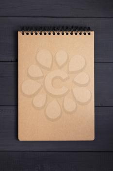 paper notebook at black wooden background surface table, top view