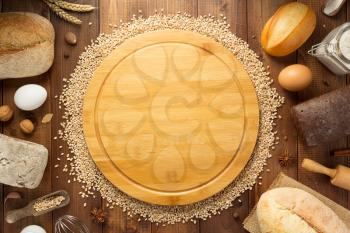 wheat grains and bakery ingredients on wooden background, top view