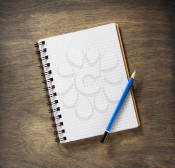 checked notebook and pencil at wooden background