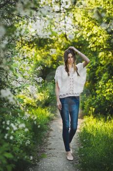 Girl in white blouse walking through the garden.