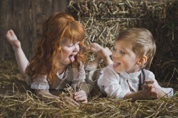 Redhead girl and boy playing with rabbit in the hay.