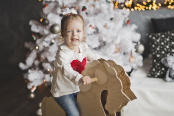 Portrait of a baby on a paper horse on the Christmas tree.