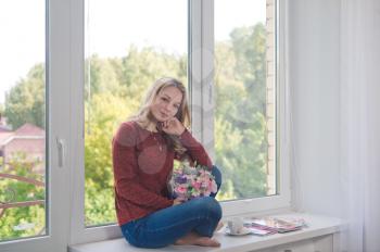 Portrait of girl sitting in yoga pose on the windowsill.