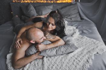 Man and woman talking while lying on a soft bed.