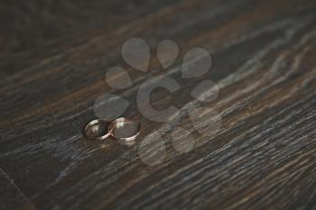 Wedding rings on a textured wooden table.