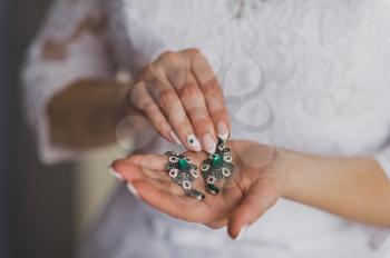 Female hand holding a beautiful green earrings.