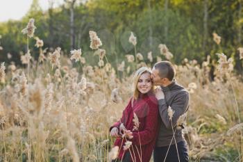 A young couple in love hugs against the background of reeds.