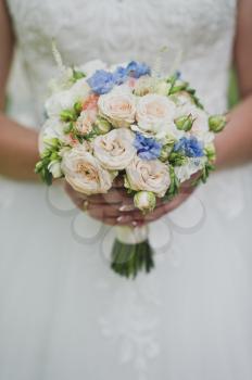 A girl in a chic white dress holding a bouquet of flowers.