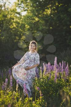 Beautiful portrait of a girl standing in the field of blooming Lupin.