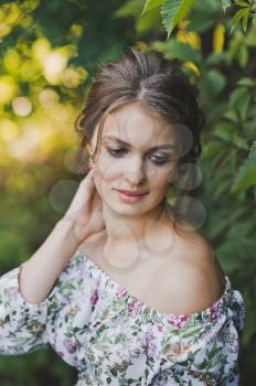 Large portrait of a girl sitting among the ivy leaves.