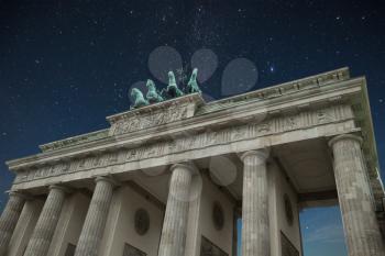 Brandenburg Gate - an architectural monument in the heart of Berlin's Mitte district. stars shine in the night sky.